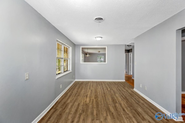 interior space with visible vents, a textured ceiling, baseboards, and wood finished floors