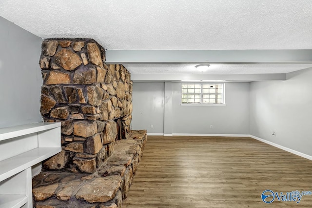 interior space featuring a textured ceiling, a fireplace, wood finished floors, and baseboards