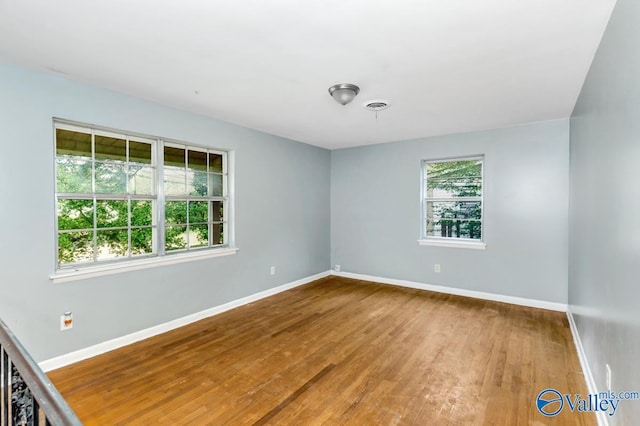 spare room with baseboards, visible vents, and wood finished floors