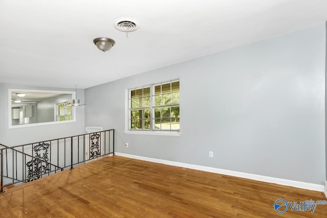 spare room featuring visible vents, baseboards, and wood finished floors