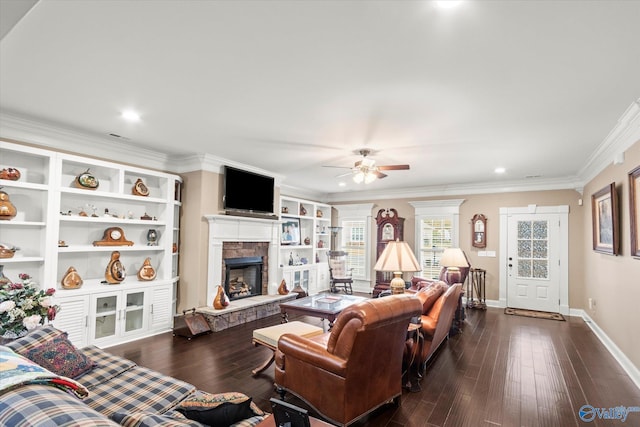 living room featuring ceiling fan, dark hardwood / wood-style floors, ornamental molding, and a fireplace