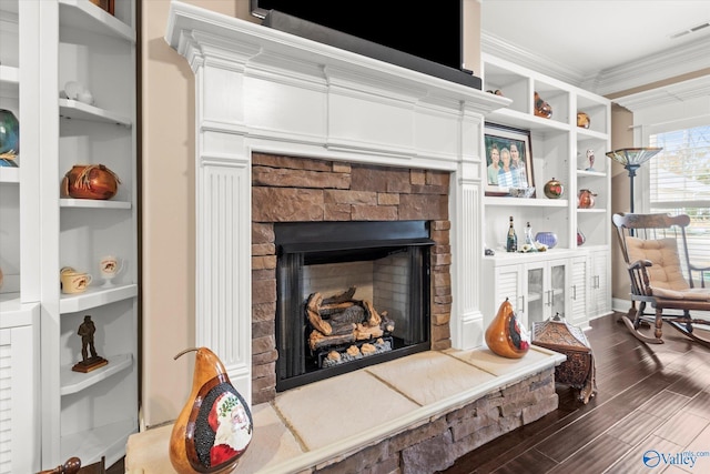 sitting room with dark hardwood / wood-style floors, a stone fireplace, crown molding, and built in shelves