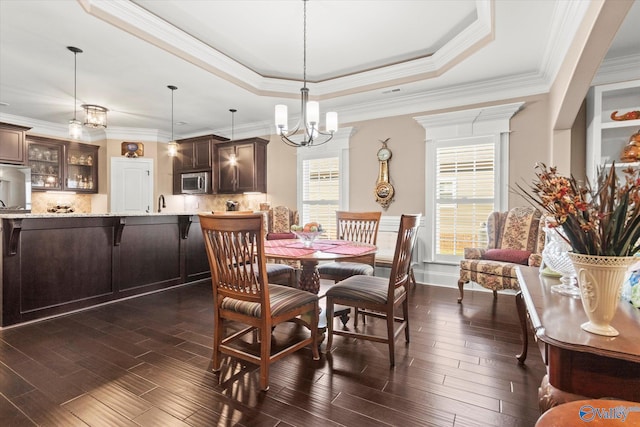 dining room with a raised ceiling, crown molding, a chandelier, and dark hardwood / wood-style floors