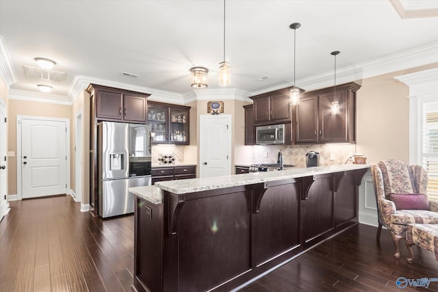 kitchen with hanging light fixtures, decorative backsplash, a kitchen bar, kitchen peninsula, and stainless steel appliances