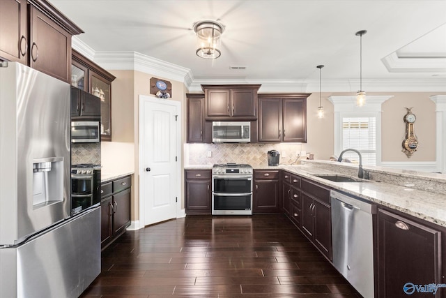 kitchen with dark brown cabinetry, sink, hanging light fixtures, stainless steel appliances, and decorative backsplash