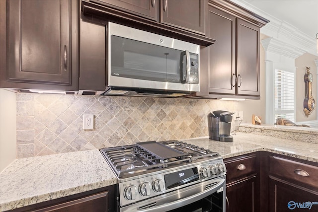 kitchen featuring decorative backsplash, appliances with stainless steel finishes, light stone countertops, and dark brown cabinets