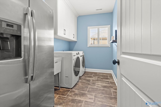 clothes washing area featuring cabinets and separate washer and dryer