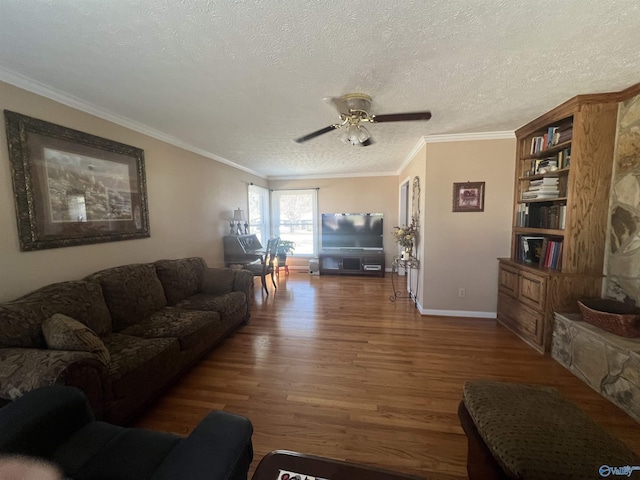 living area featuring a ceiling fan, wood finished floors, baseboards, ornamental molding, and a textured ceiling