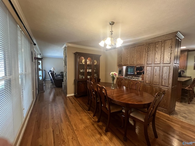 dining area featuring ornamental molding, a textured ceiling, an inviting chandelier, baseboards, and dark wood-style flooring