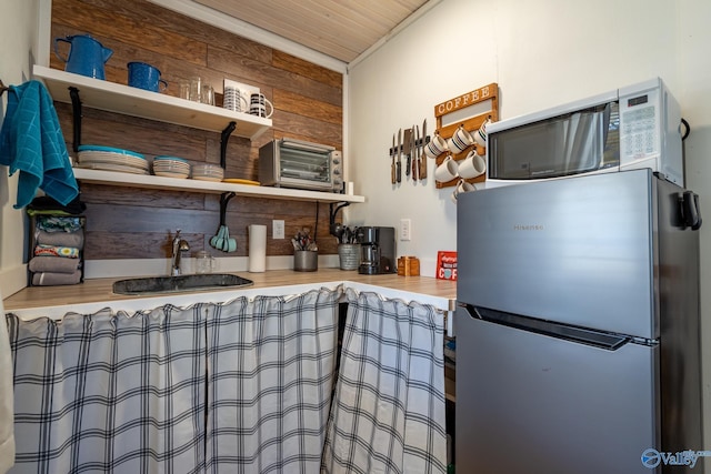 kitchen with sink, wood ceiling, and stainless steel refrigerator