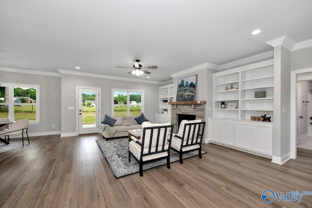 living room with ceiling fan, crown molding, light hardwood / wood-style floors, and a fireplace