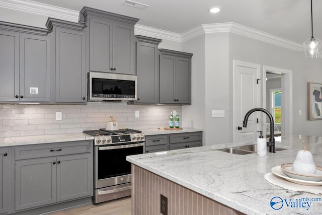 kitchen featuring light stone counters, stainless steel appliances, gray cabinets, decorative backsplash, and sink