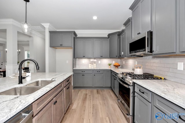 kitchen with light stone counters, ornamental molding, stainless steel appliances, decorative light fixtures, and light hardwood / wood-style flooring