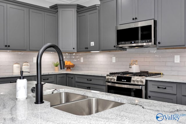 kitchen with decorative backsplash, appliances with stainless steel finishes, gray cabinets, and sink