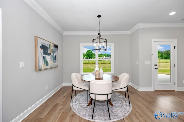 dining area featuring light hardwood / wood-style flooring, a notable chandelier, ornamental molding, and plenty of natural light