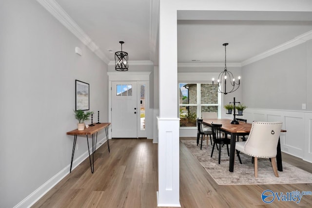 entrance foyer with light wood-type flooring, a notable chandelier, and crown molding