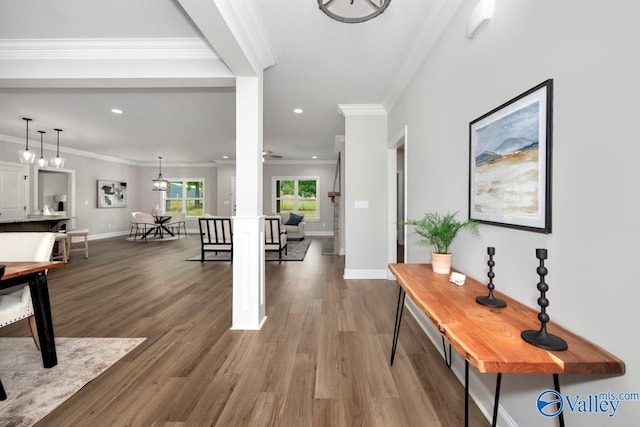 foyer featuring dark wood-type flooring, crown molding, and decorative columns