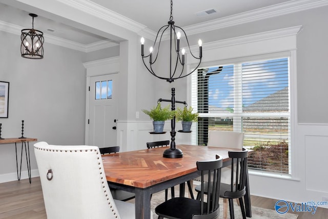 dining space with an inviting chandelier, wood-type flooring, and ornamental molding