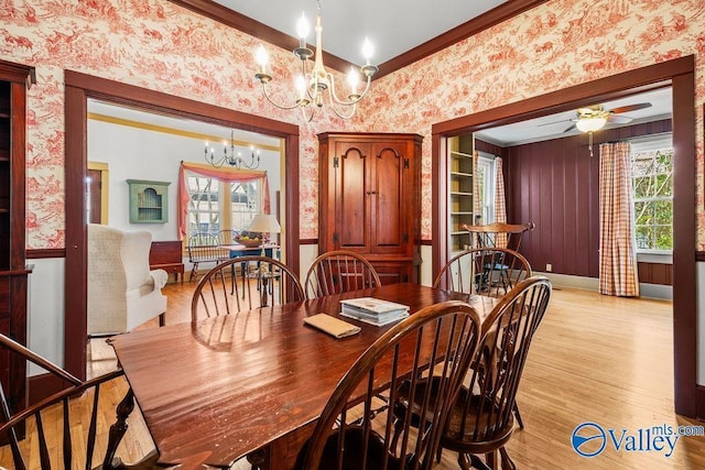 dining area featuring ornamental molding, ceiling fan with notable chandelier, light wood-style floors, wallpapered walls, and baseboards