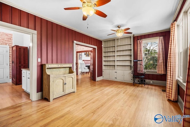 unfurnished office featuring baseboards, wooden walls, light wood-style flooring, and crown molding