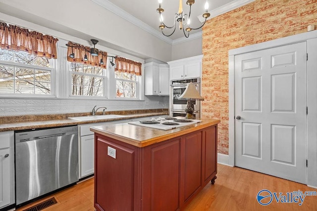 kitchen with visible vents, light wood-style flooring, a sink, appliances with stainless steel finishes, and crown molding