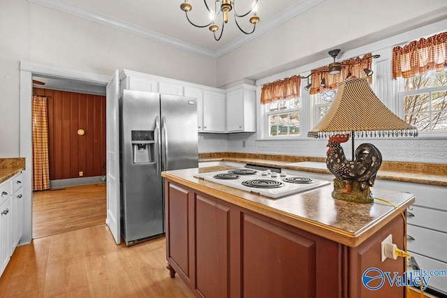 kitchen featuring a kitchen island, crown molding, stainless steel fridge, white cabinets, and white electric stovetop