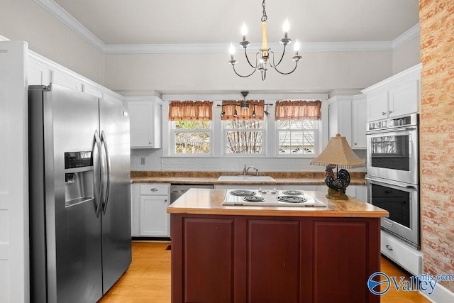 kitchen featuring a sink, appliances with stainless steel finishes, a wealth of natural light, and white cabinetry