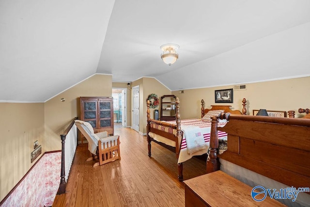 bedroom with light wood finished floors, visible vents, baseboards, and lofted ceiling