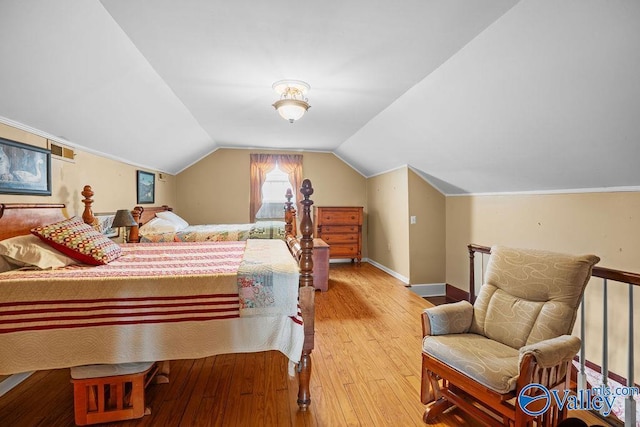 bedroom with light wood finished floors, baseboards, and lofted ceiling