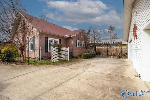 view of home's exterior featuring concrete driveway, fence, and metal roof