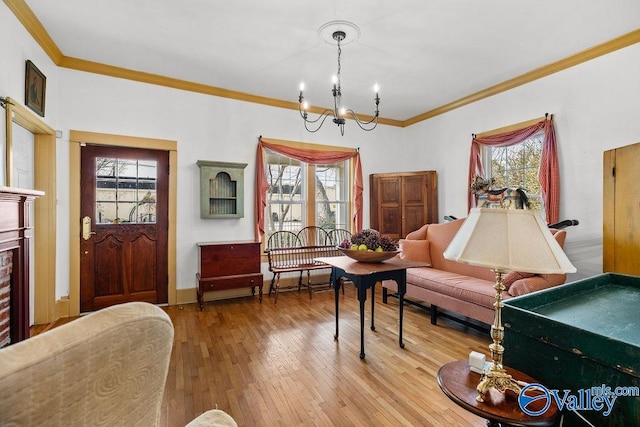 living area featuring baseboards, a notable chandelier, crown molding, and hardwood / wood-style flooring