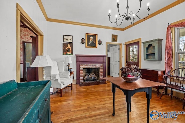 living area with a notable chandelier, a fireplace, crown molding, and wood finished floors