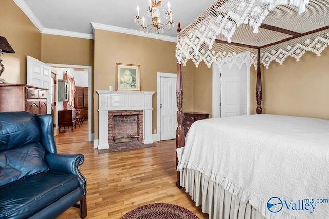 bedroom featuring crown molding, a brick fireplace, a notable chandelier, and light wood-style flooring