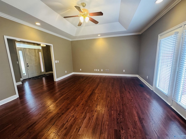 spare room with a ceiling fan, dark wood-type flooring, and a raised ceiling