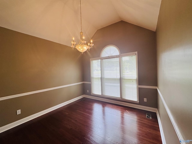 spare room featuring wood finished floors, a notable chandelier, visible vents, baseboards, and lofted ceiling