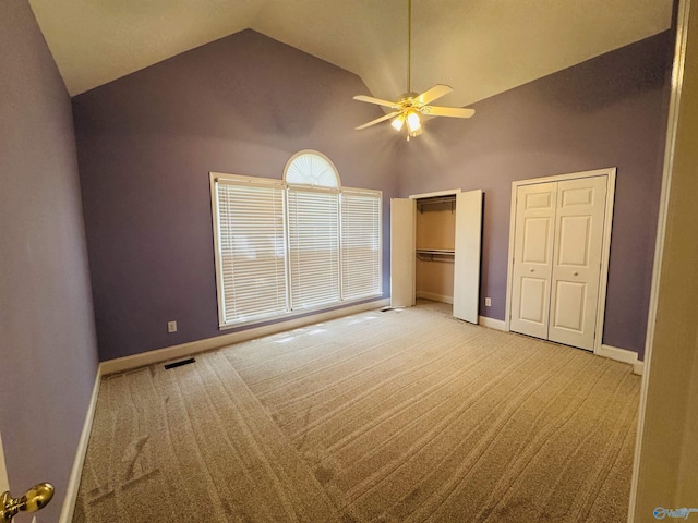 unfurnished bedroom featuring lofted ceiling, multiple closets, visible vents, light carpet, and baseboards