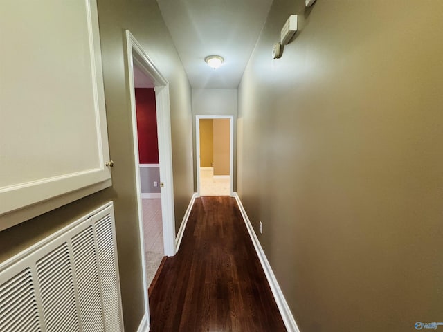 hallway with dark wood-type flooring, baseboards, and visible vents