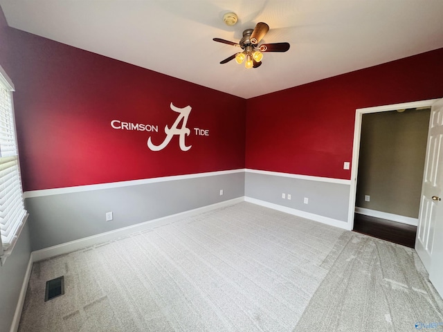 carpeted empty room with baseboards, a ceiling fan, and visible vents