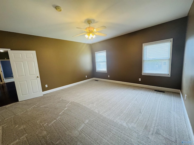 carpeted empty room featuring visible vents, baseboards, and ceiling fan