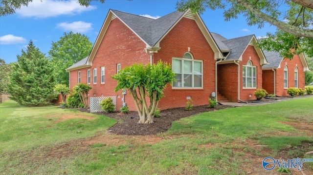 view of side of home with a yard, roof with shingles, and brick siding