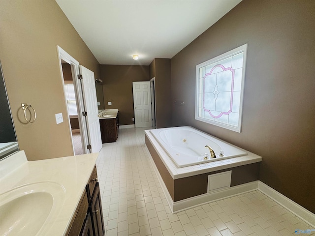 bathroom featuring a tub with jets, two vanities, baseboards, and tile patterned floors