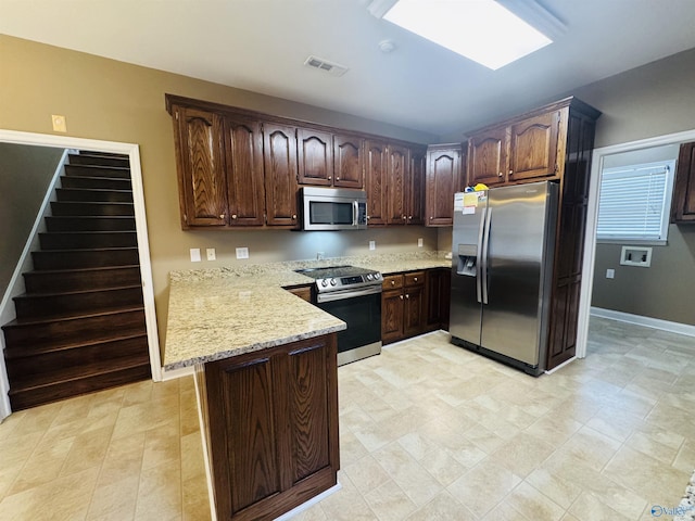 kitchen with light stone countertops, visible vents, dark brown cabinetry, a peninsula, and stainless steel appliances