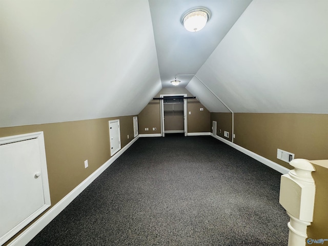 additional living space with vaulted ceiling, baseboards, visible vents, and dark colored carpet