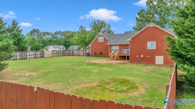 view of yard featuring a deck, a fenced backyard, and stairs