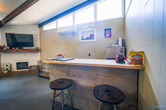 bar featuring lofted ceiling with beams, wooden walls, and a wealth of natural light