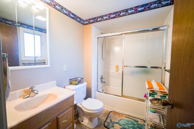 full bathroom featuring bath / shower combo with glass door, a textured ceiling, toilet, vanity, and tile patterned floors