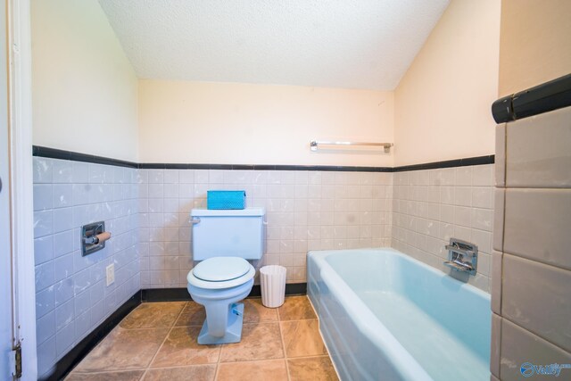 bathroom with tile walls, toilet, tile patterned floors, and a textured ceiling