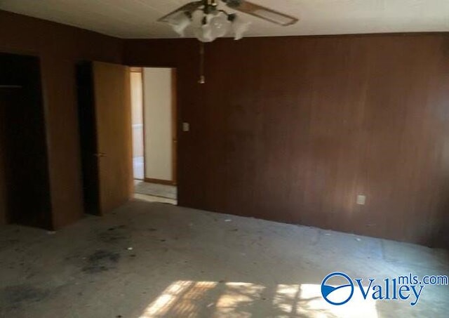 empty room featuring wood walls and ceiling fan