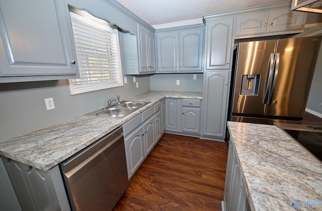 kitchen with dark hardwood / wood-style flooring, appliances with stainless steel finishes, a textured ceiling, ornamental molding, and light stone counters