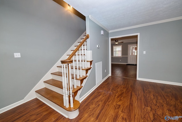 stairs with ceiling fan, ornamental molding, a textured ceiling, and hardwood / wood-style floors